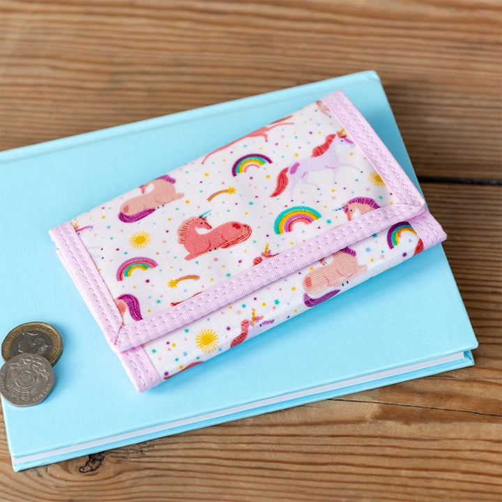 Rex Unicorn wallet on blue notebook with coins